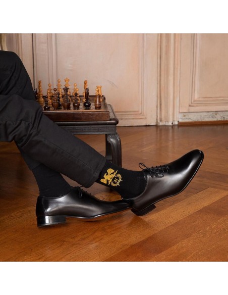 homme élégant portant des chaussettes Napoléon avec un aigle impérial près d'un échiquier